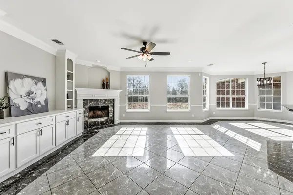 a view of a livingroom with a fireplace a ceiling fan and windows