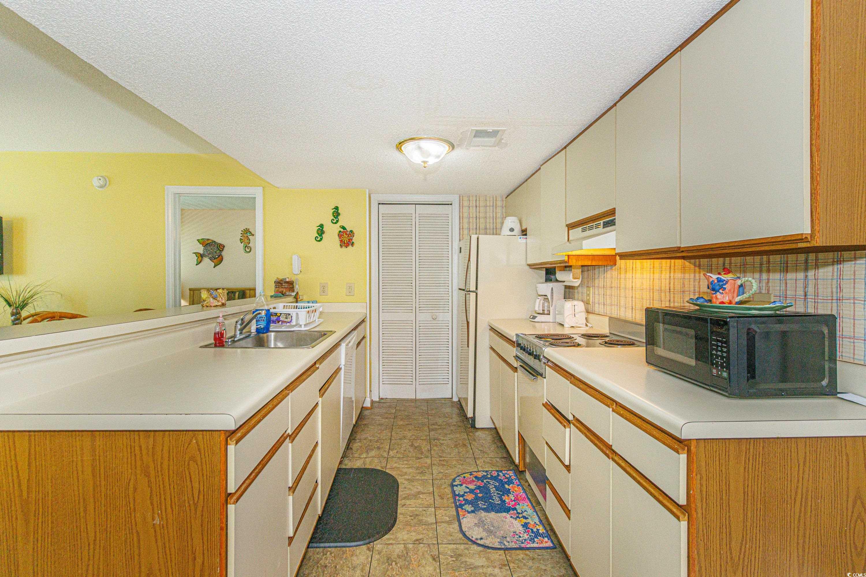 5905 South Kings Highway, Unit 4215 Myrtle Beach, SC 29575 - Photo 8 of 40 Kitchen with a peninsula, a textured ceiling, black microwave, electric range, and light countertops