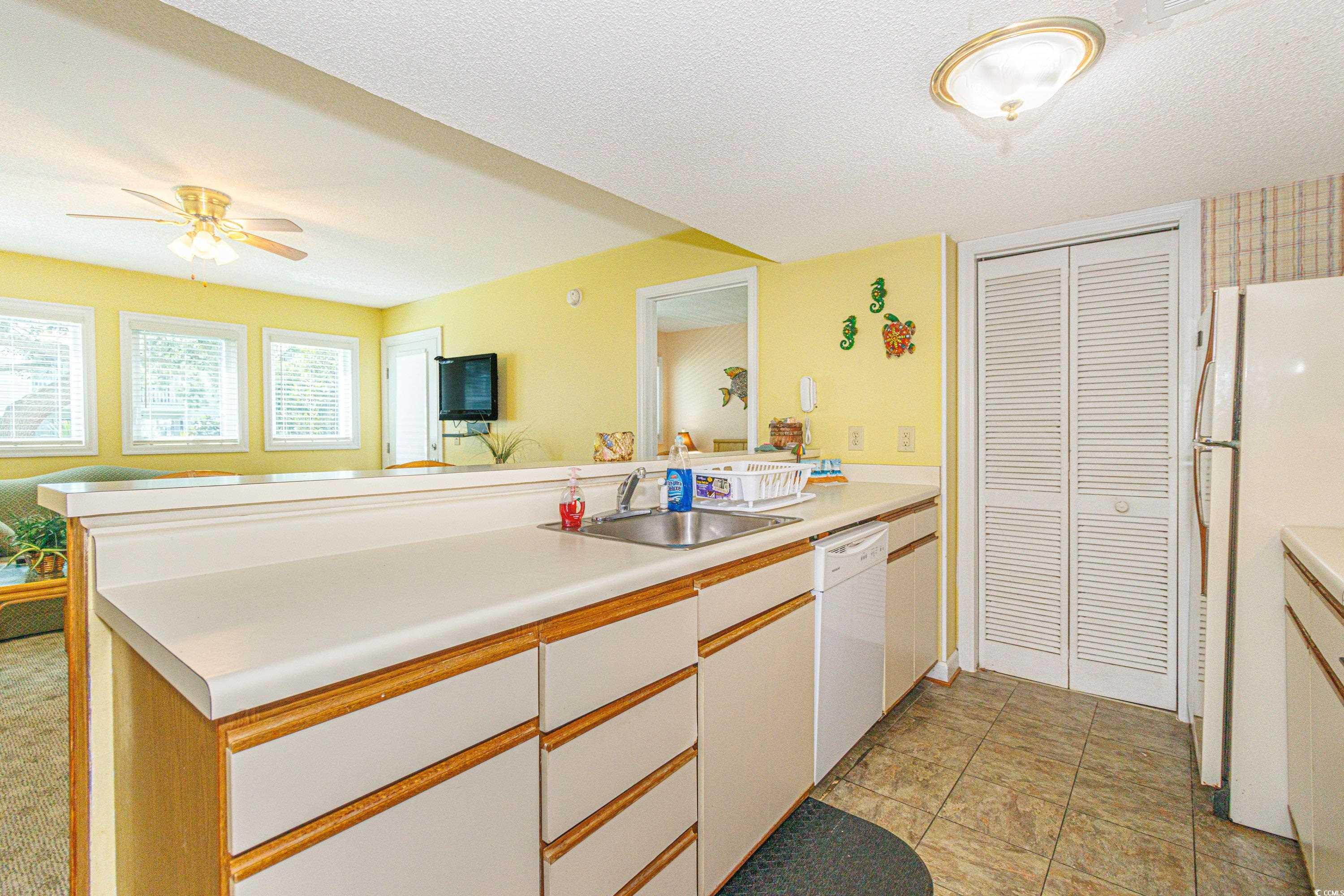 5905 South Kings Highway, Unit 4215 Myrtle Beach, SC 29575 - Photo 9 of 40 Kitchen with a peninsula, light countertops, white appliances, a textured ceiling, and white cabinetry