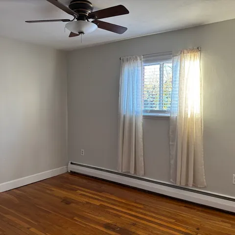 an empty room with wooden floor cabinet and windows