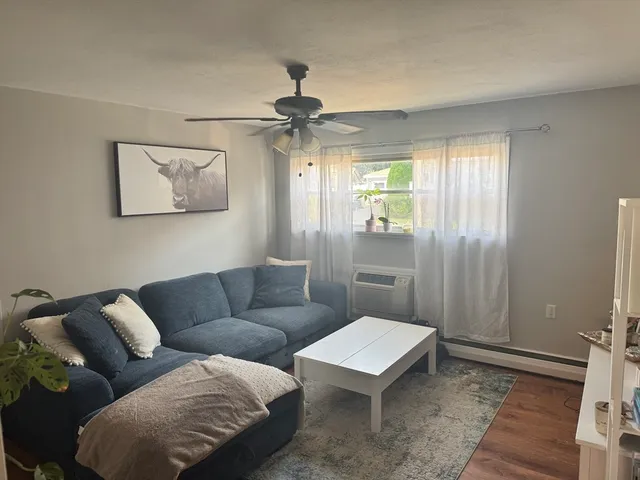 a living room with furniture a window and a ceiling fan