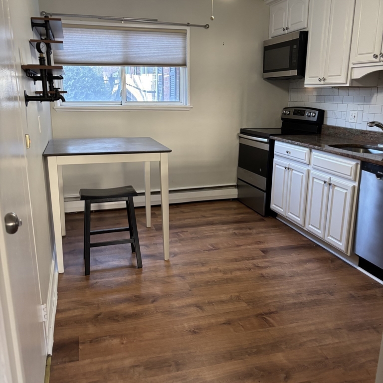 701 Adams Street, Unit 9 Boston, MA 02122 - Photo 6 of 19 a kitchen with granite countertop a stove a sink and a microwave