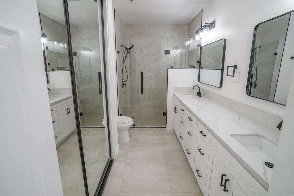 5845 Friars Road, Unit 1316 San Diego, CA 92110 - Photo 22 of 29 a spacious bathroom with a double vanity sink toilet mirror and shower
