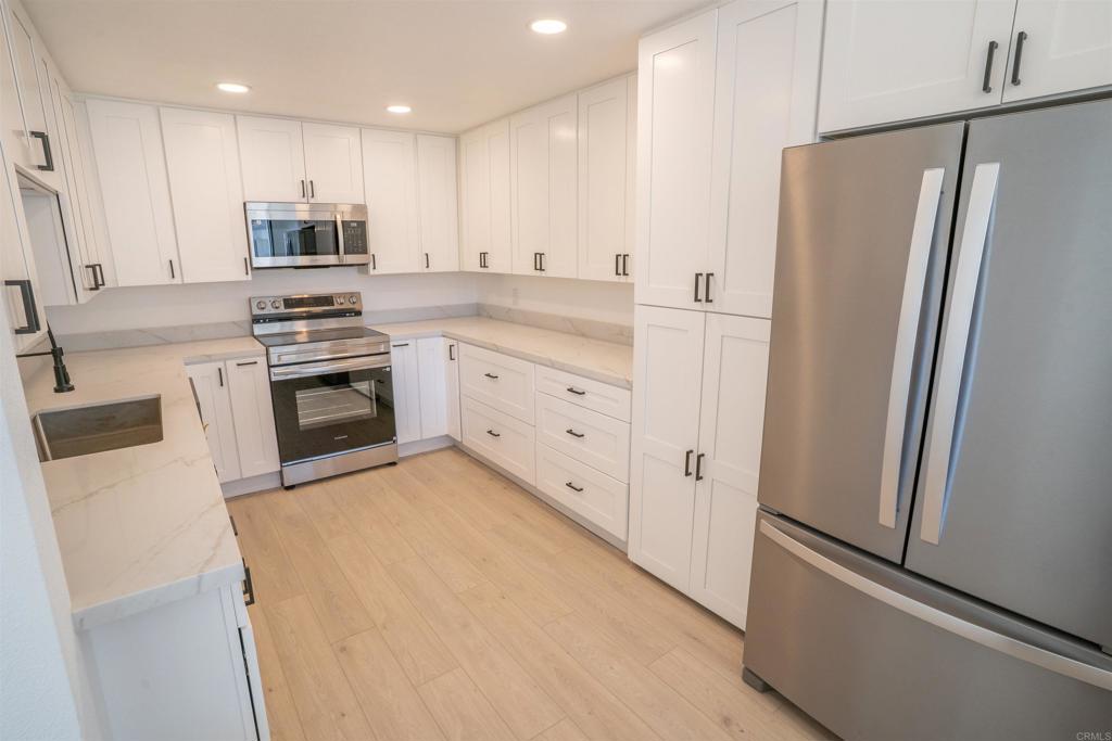 5845 Friars Road, Unit 1316 San Diego, CA 92110 - Photo 10 of 29 a kitchen with stainless steel appliances white cabinets and wooden floors
