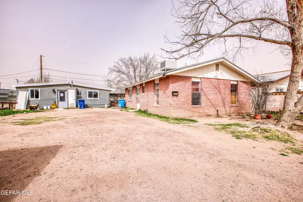 a front view of a house with a dirt yard and covered outdoor space