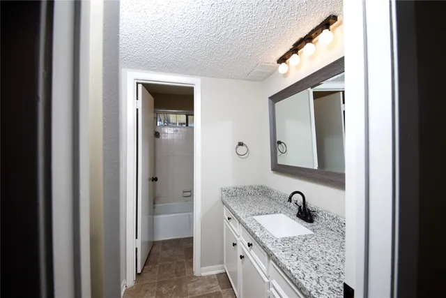 a bathroom with a granite countertop sink and a mirror