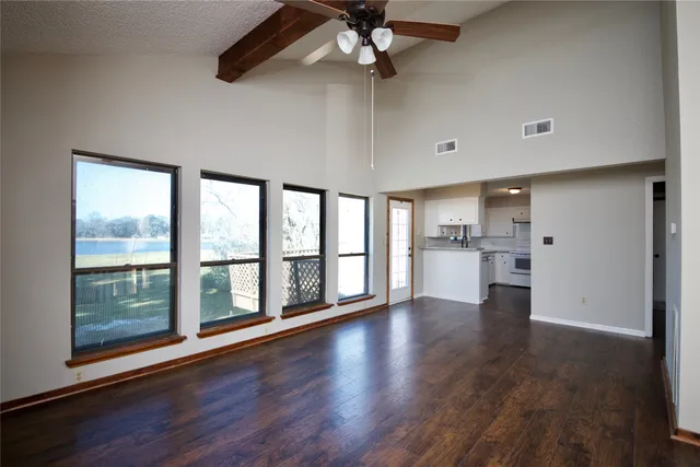 a view of an empty room with a window and wooden floor