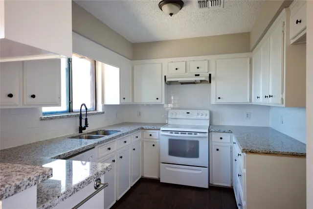 a kitchen with white cabinets and sink