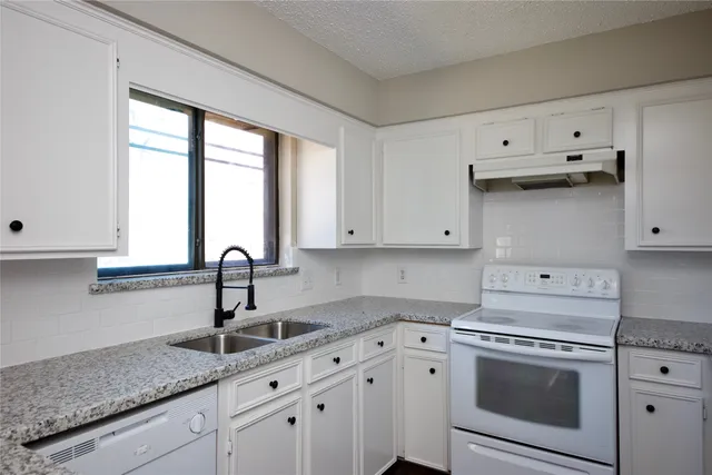 a kitchen with granite countertop white cabinets and a sink