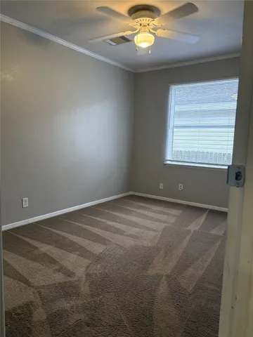 an empty room with a chandelier fan and windows