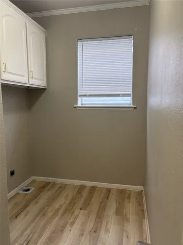 a view of an empty room with wooden floor and cabinets