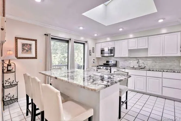 a kitchen with stainless steel appliances granite countertop a sink a stove a dining table and chairs