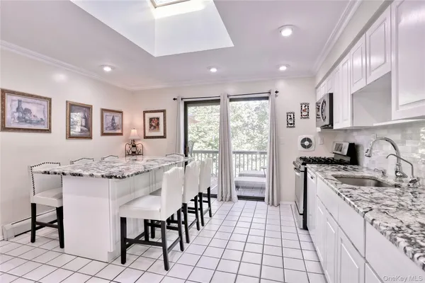 a kitchen with kitchen island granite countertop a stove a sink a dining table and chairs