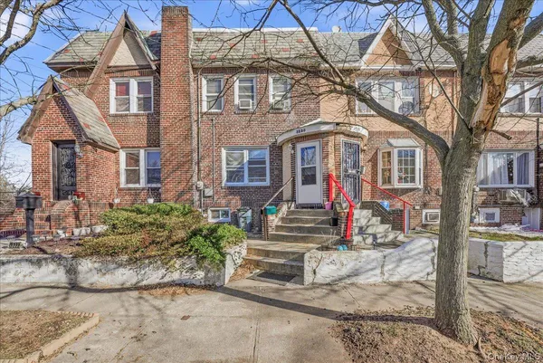 a view of a white house with large tree and wooden fence
