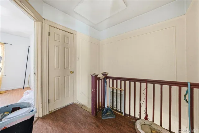 a view of a hallway with wooden floor and a bathroom