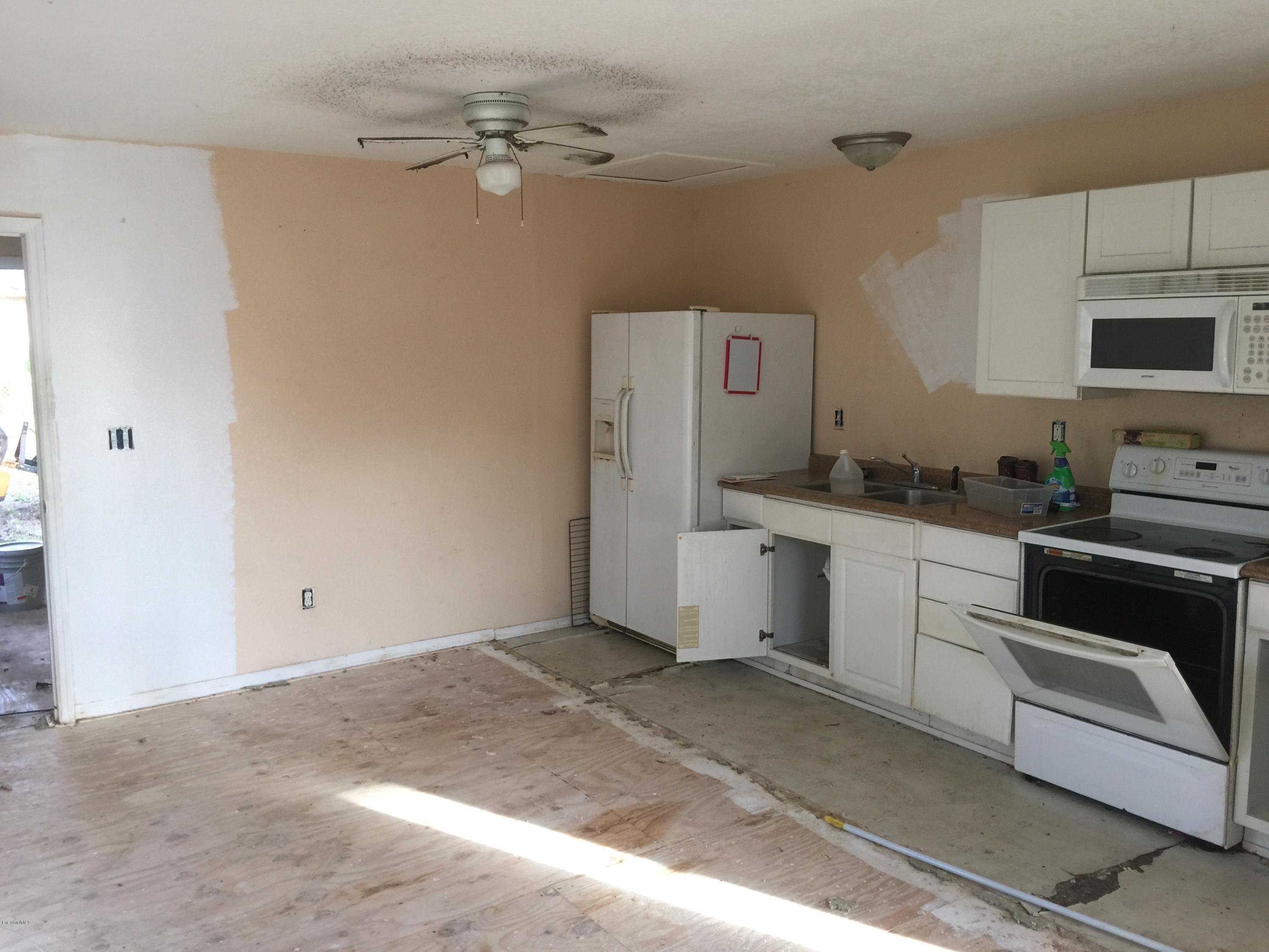 623 Roderick A Harris Sr. Avenue, Unit A Titusville, FL 32796 - Photo 5 of 6 a kitchen with a refrigerator stove and white cabinets