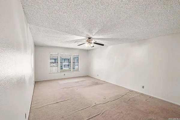 an empty room with windows and fan