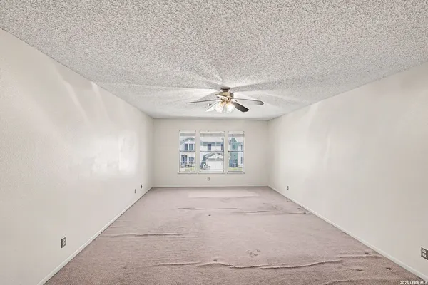 an empty room with windows and fan