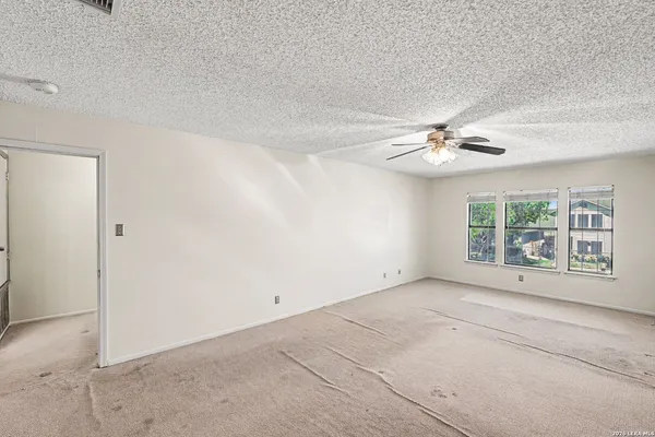 an empty room with windows and chandelier fan