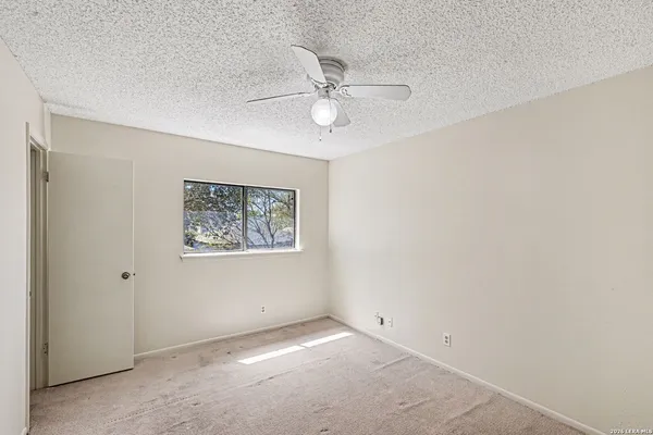 an empty room with a window and ceiling fan