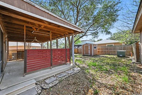 a view of a backyard with plants and large trees