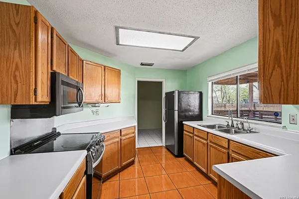 a kitchen with stainless steel appliances granite countertop a sink and dishwasher a refrigerator with wooden cabinets