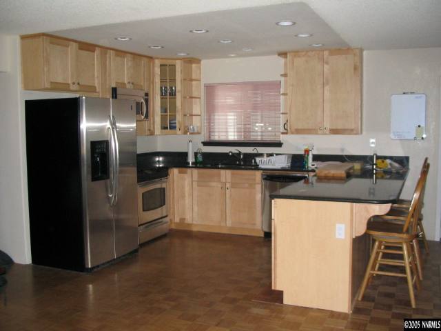 5914 Grass Valley Road Reno, NV 89510 - Photo 3 of 7 a kitchen with granite countertop a refrigerator a stove a sink and white cabinets
