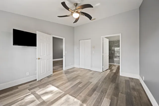 a view of empty room with wooden floor and fan