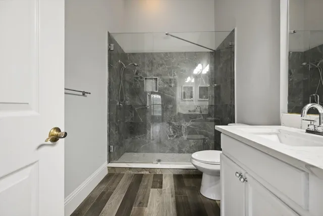 a bathroom with a sink a toilet a mirror and shower