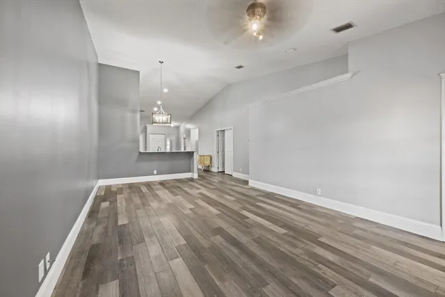 an empty room with wooden floor and windows