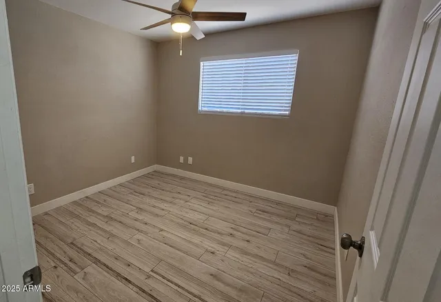 en empty room with wooden floor and fan