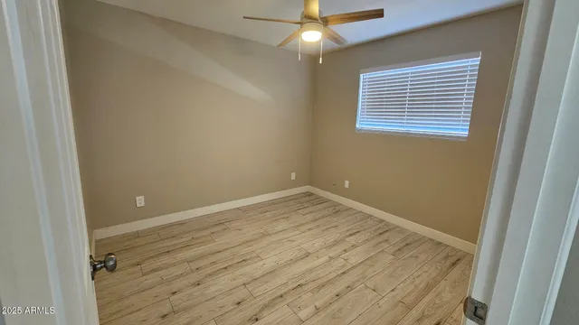 en empty room with wooden floor and fan
