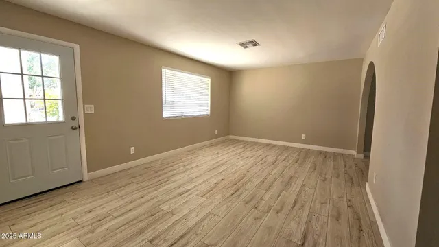 an empty room with wooden floor and windows