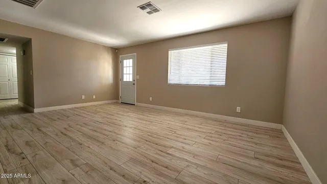 an empty room with wooden floor and windows