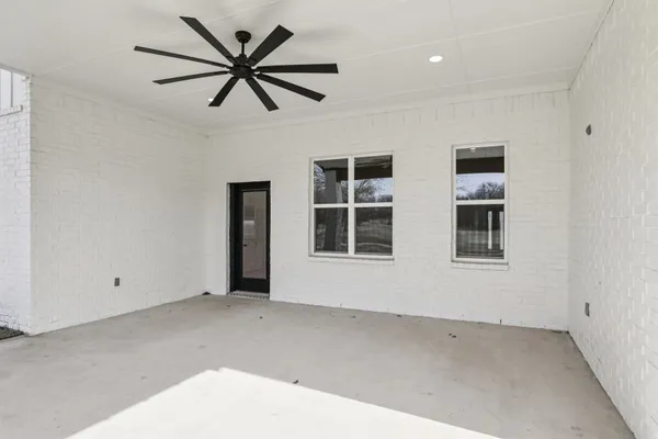 a view of an empty room with chandelier fan and windows