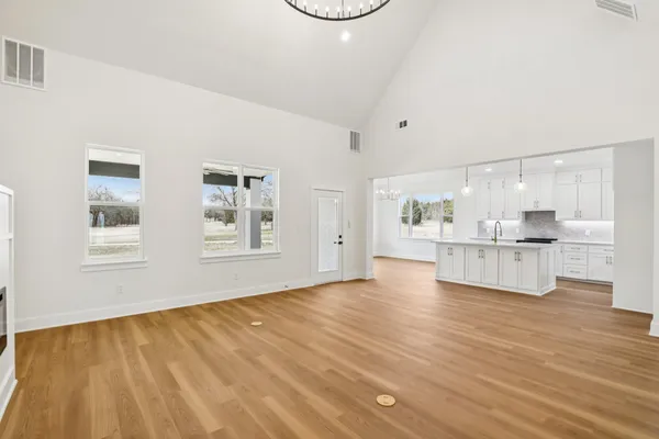 a view of kitchen and empty room with wooden floor
