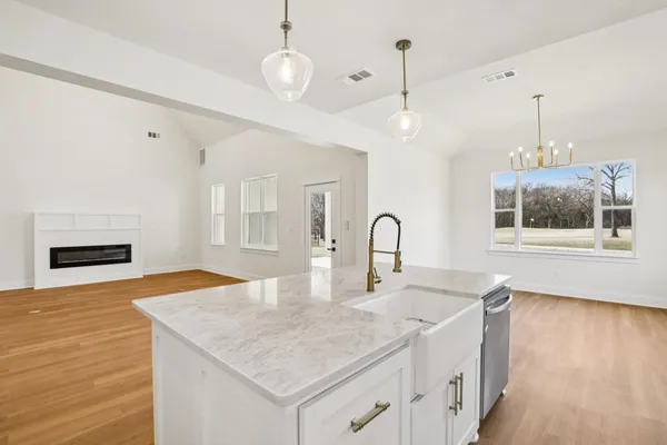 a kitchen with stainless steel appliances granite countertop a sink a microwave cabinets and a wooden floor