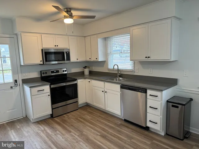 a kitchen with stainless steel appliances granite countertop a sink a stove a microwave and wooden floors