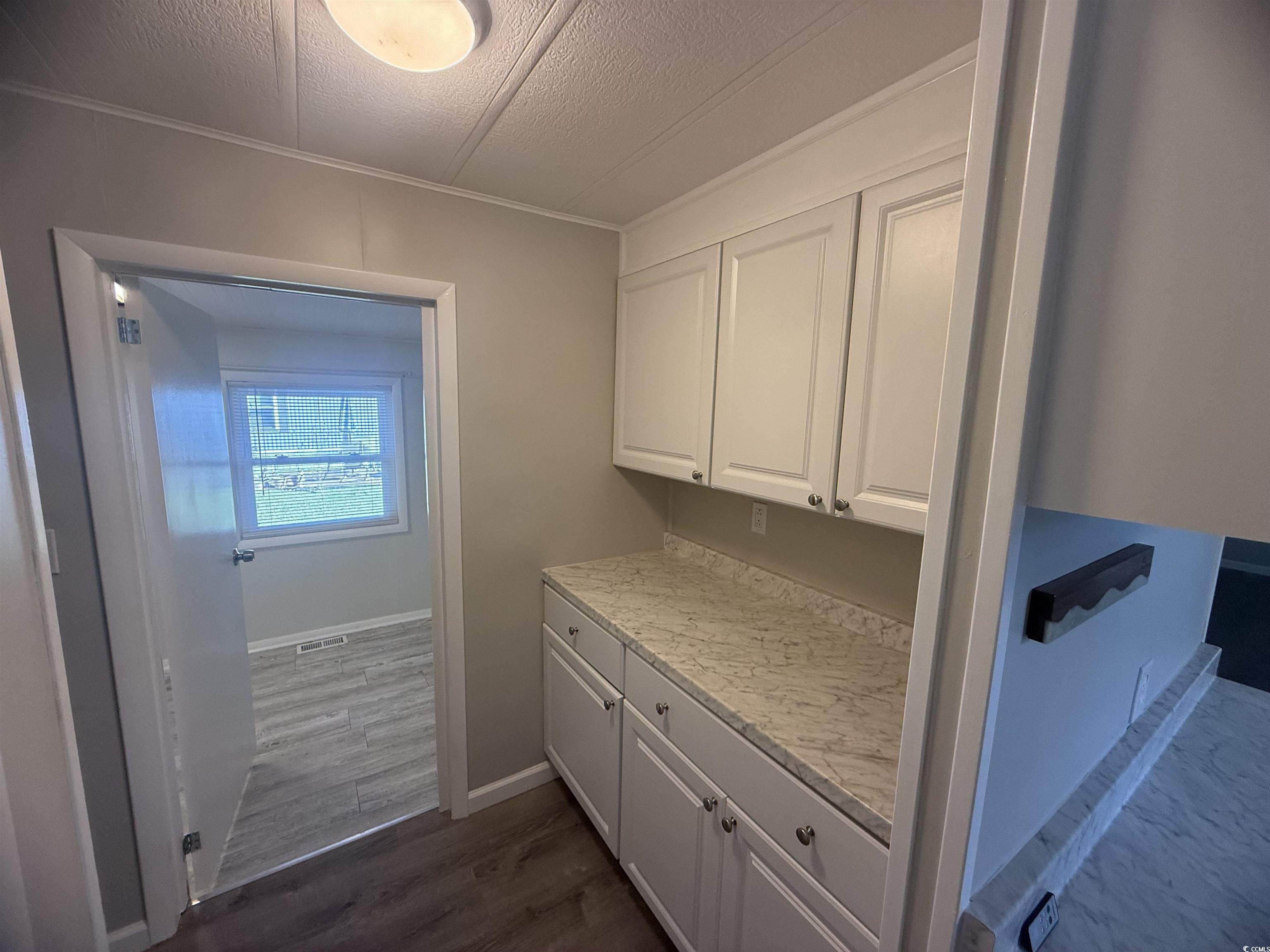 826 Jensen Drive North Murrells Inlet, SC 29576 - Photo 12 of 38 Kitchen with light countertops, white cabinets, dark wood-style floors, crown molding, and a textured ceiling