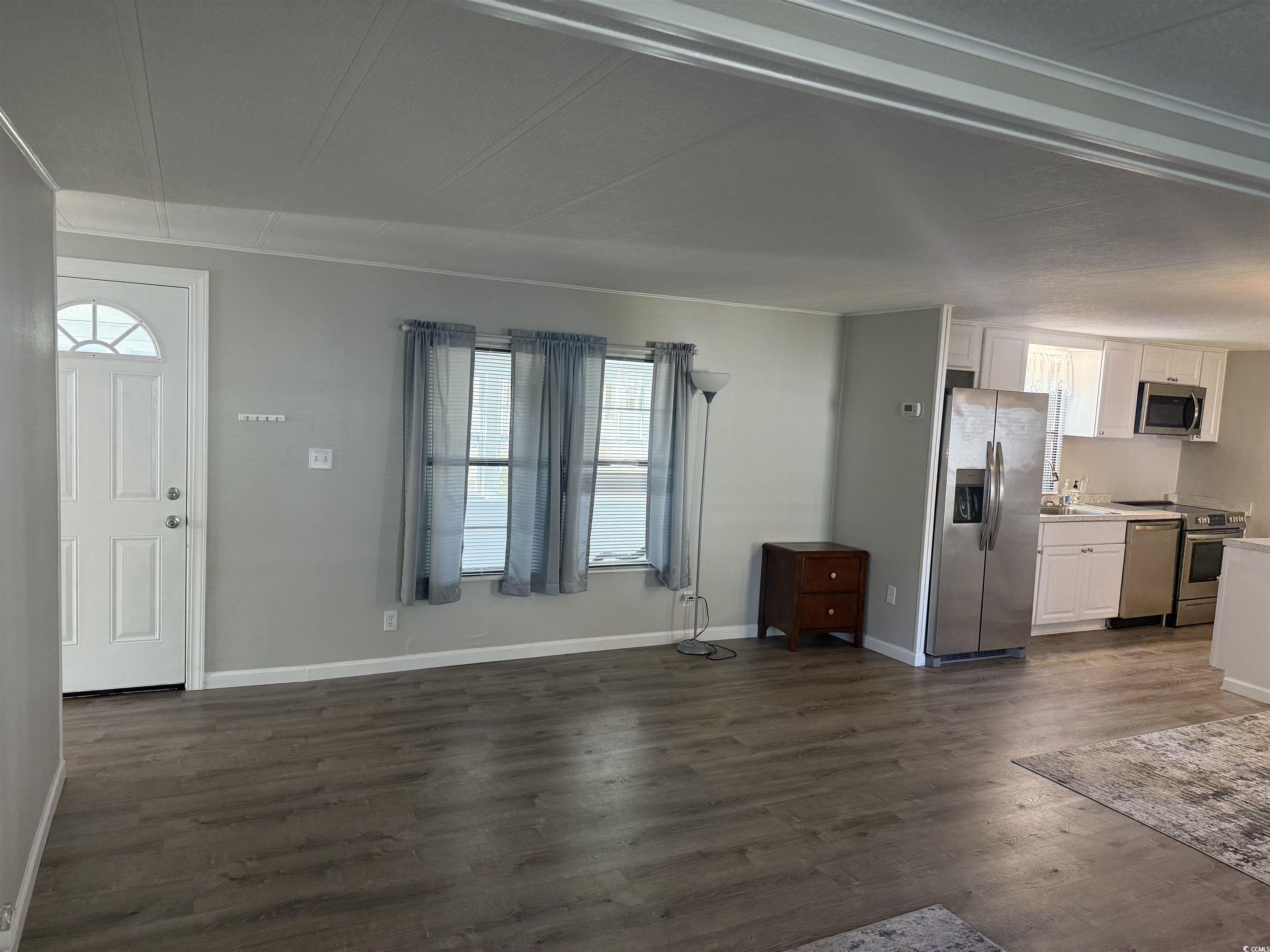 826 Jensen Drive North Murrells Inlet, SC 29576 - Photo 16 of 38 Unfurnished living room featuring dark wood-style floors and baseboards
