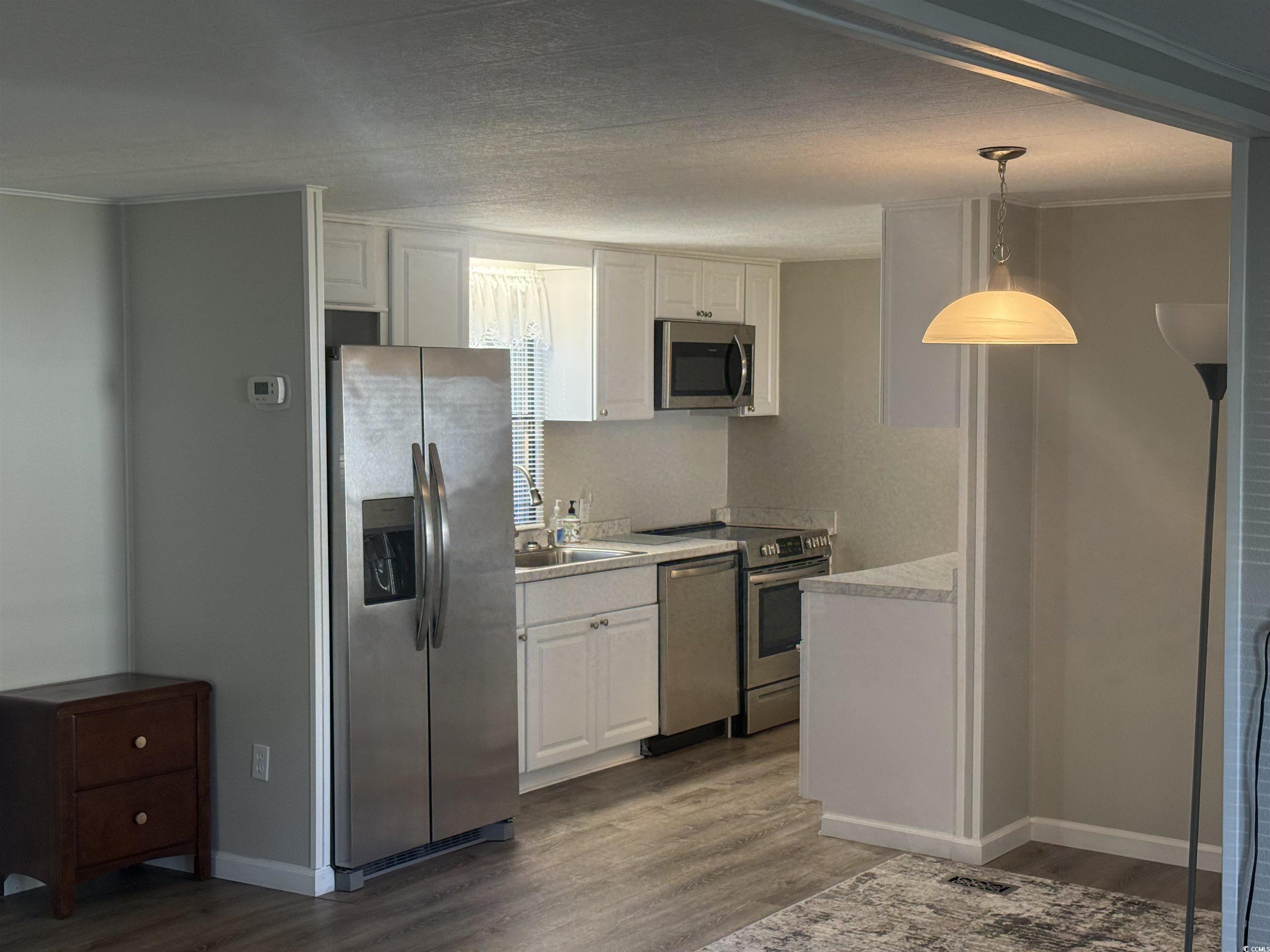 826 Jensen Drive North Murrells Inlet, SC 29576 - Photo 18 of 38 Kitchen with stainless steel appliances, white cabinets, dark wood-type flooring, light countertops, and pendant lighting