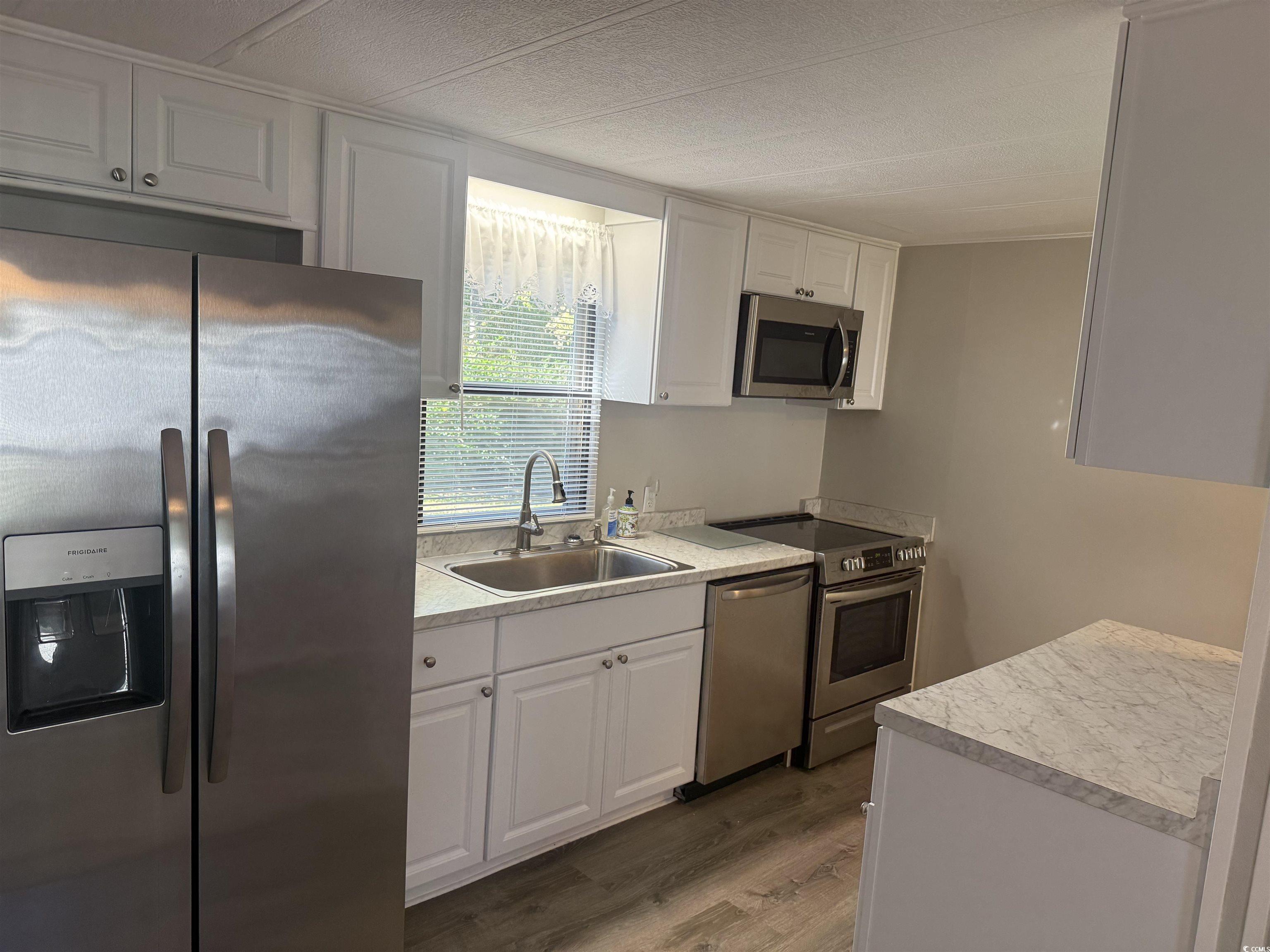 826 Jensen Drive North Murrells Inlet, SC 29576 - Photo 21 of 38 Kitchen featuring stainless steel appliances, light countertops, white cabinetry, and dark wood-style flooring
