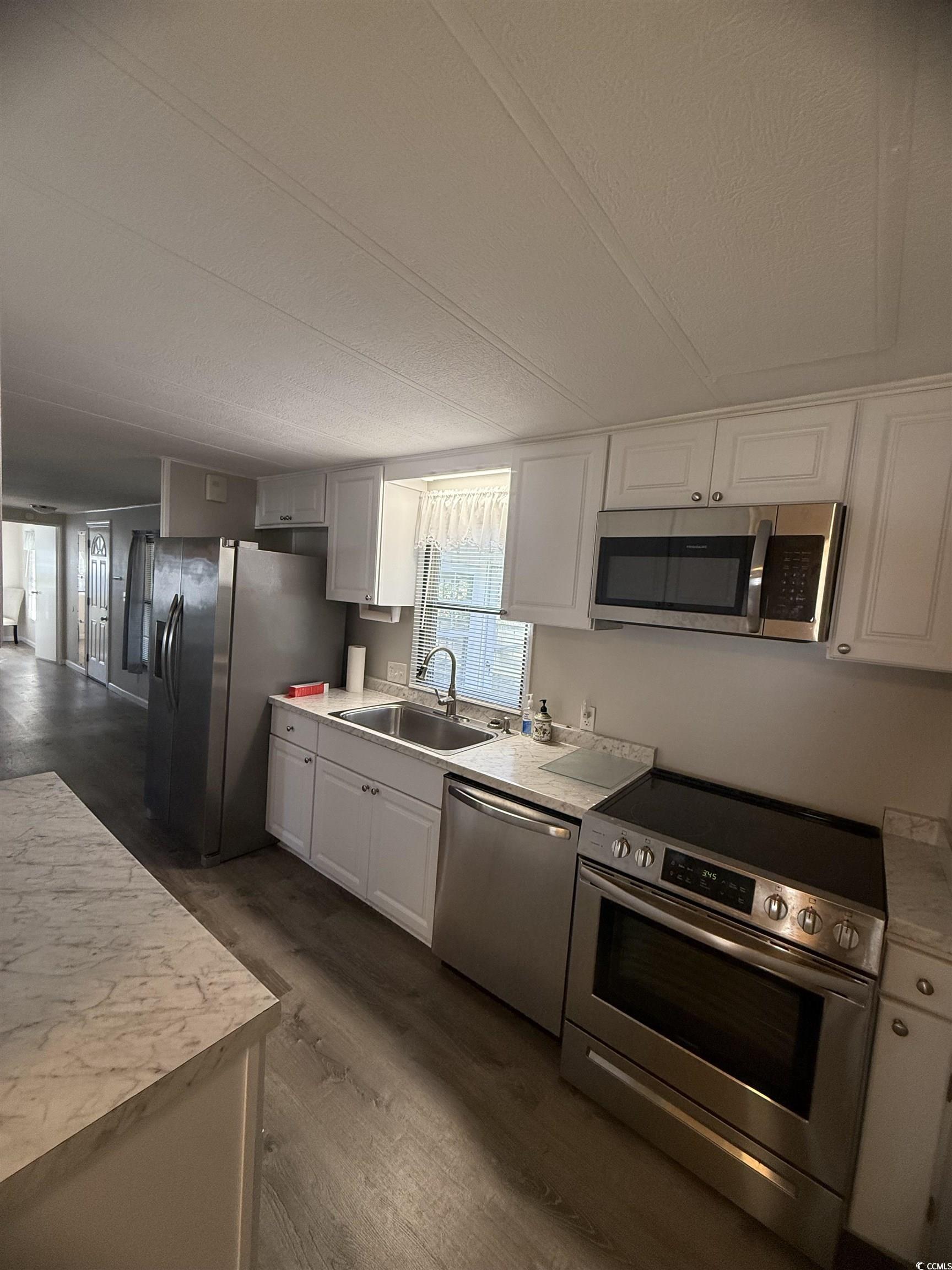 826 Jensen Drive North Murrells Inlet, SC 29576 - Photo 24 of 38 Kitchen featuring stainless steel appliances, light countertops, white cabinetry, dark wood-type flooring, and a textured ceiling