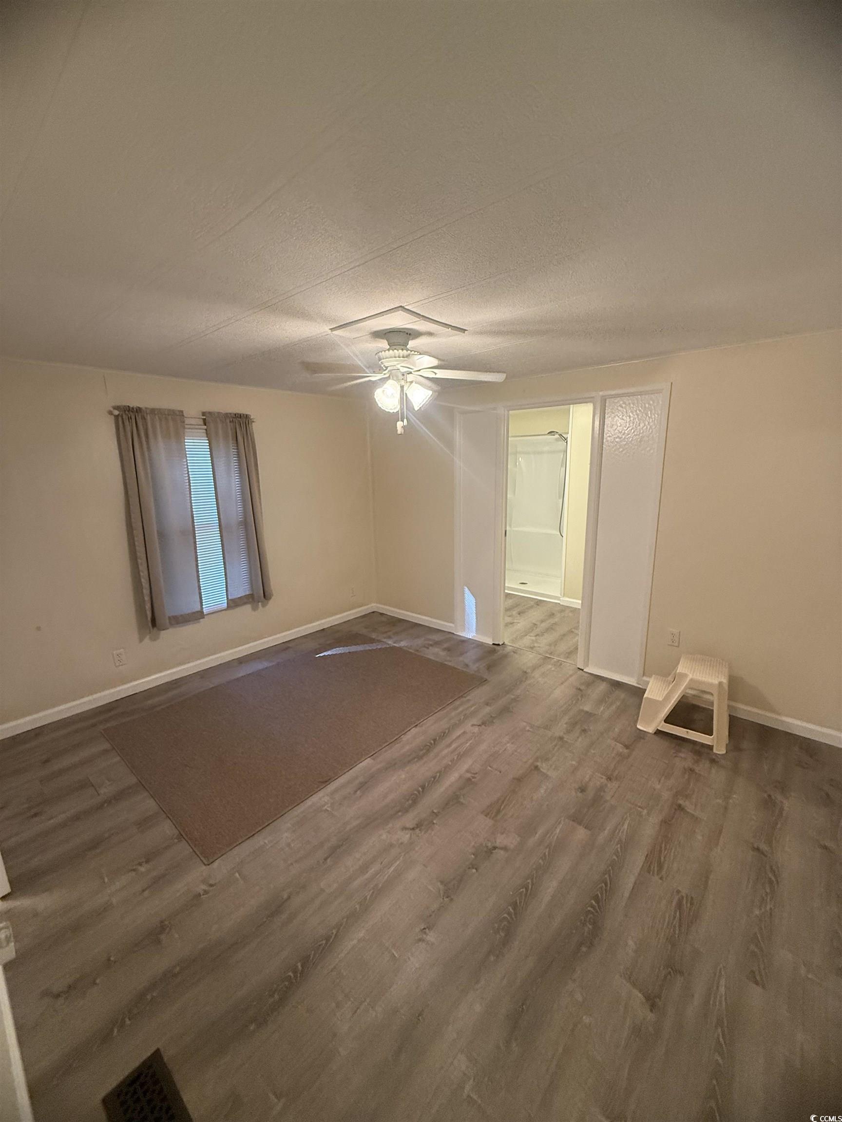 826 Jensen Drive North Murrells Inlet, SC 29576 - Photo 28 of 38 Empty room with dark wood-style floors, ceiling fan, and a textured ceiling