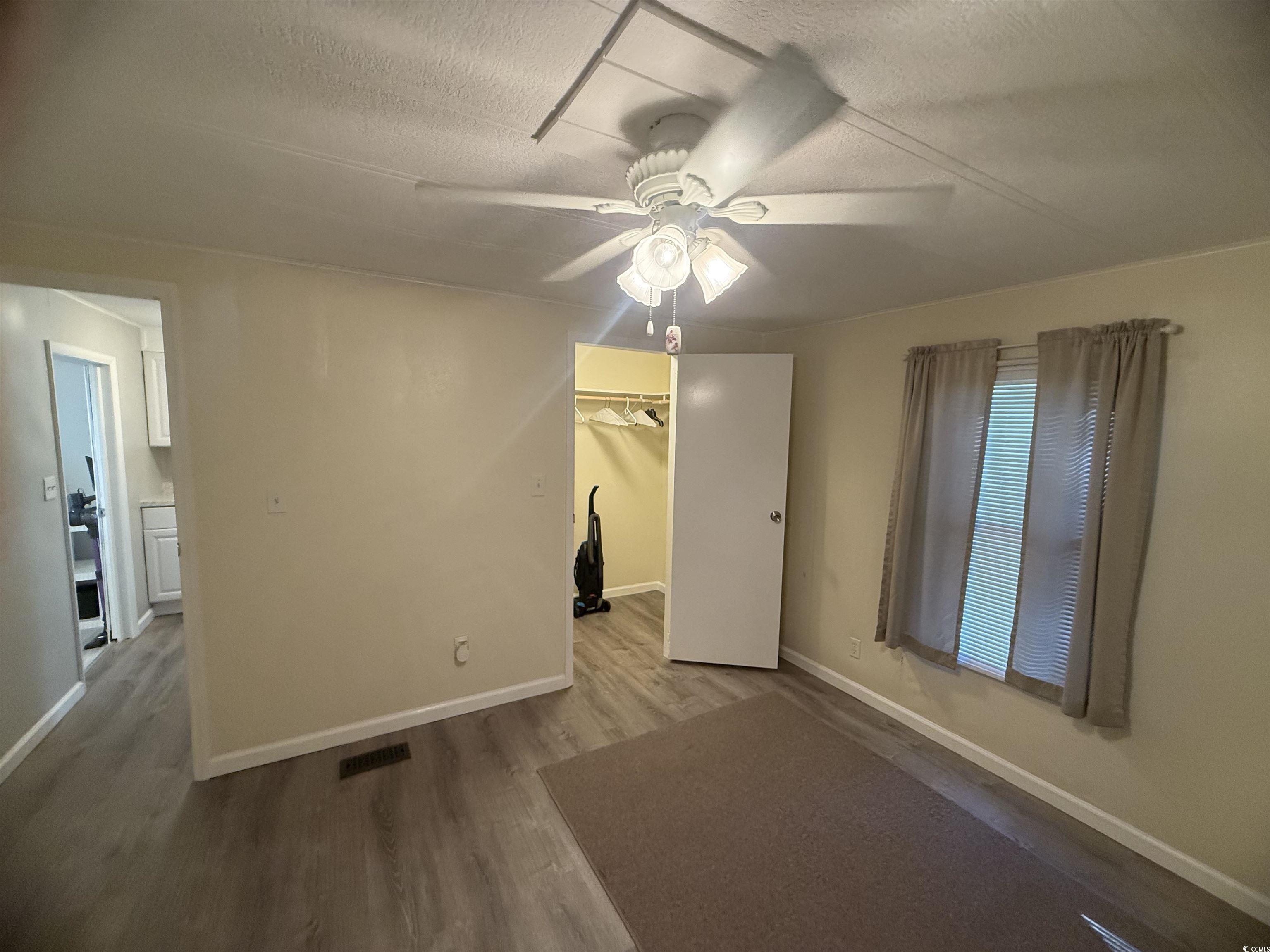 826 Jensen Drive North Murrells Inlet, SC 29576 - Photo 29 of 38 Unfurnished bedroom with wood finished floors, a textured ceiling, a spacious closet, and a ceiling fan