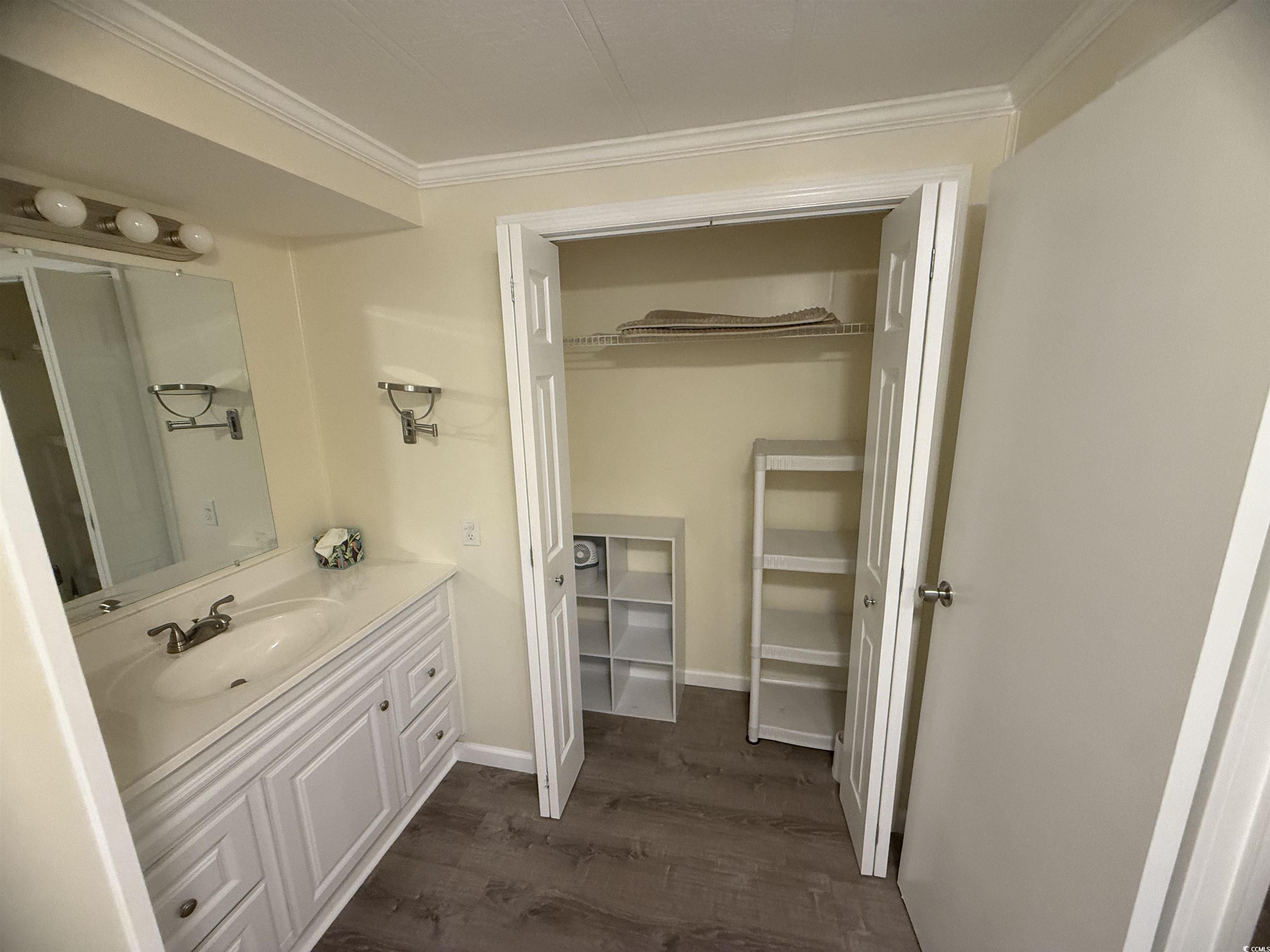 826 Jensen Drive North Murrells Inlet, SC 29576 - Photo 34 of 38 Bathroom with crown molding, vanity, dark wood finished floors, and a walk in closet