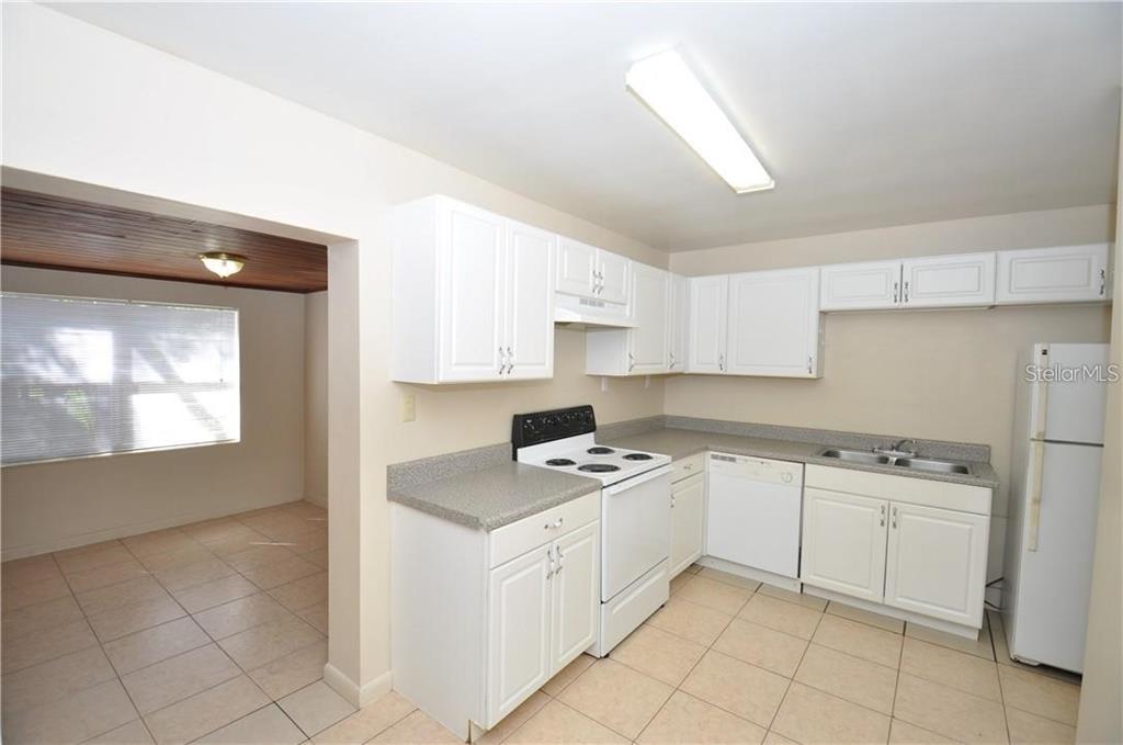 509 Norfolk Circle Lakeland, FL 33801 - Photo 7 of 14 a kitchen with white cabinets a sink stove and white countertops with wooden floor