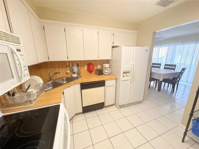 a kitchen with a sink a stove a refrigerator and white cabinets