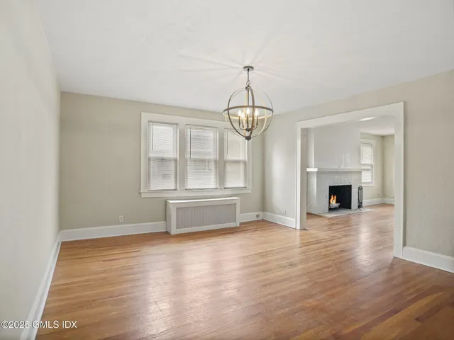 an empty room with wooden floor fireplace and windows
