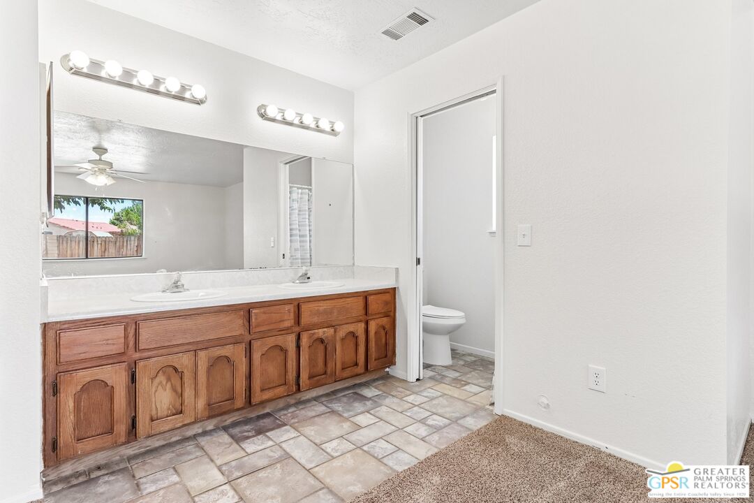 13819 Rivers Edge Road Helendale, CA 92342 - Photo 14 of 31 a spacious bathroom with a double vanity sink a toilet and a mirror